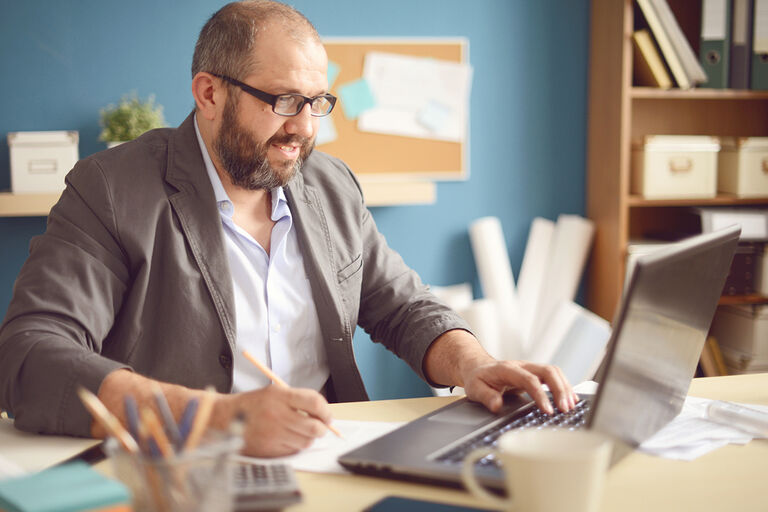 Mann mit Laptop am Schreibtisch